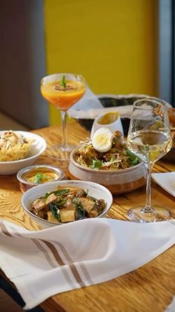 Indian cuisine dishes and drinks served on a wooden table with a white cloth in an East Village restaurant.