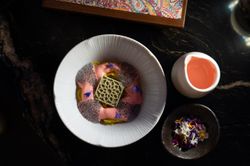 Plated dessert with textured garnish, pink sauce, and side flowers and pink drink served at Jazba Indian restaurant.