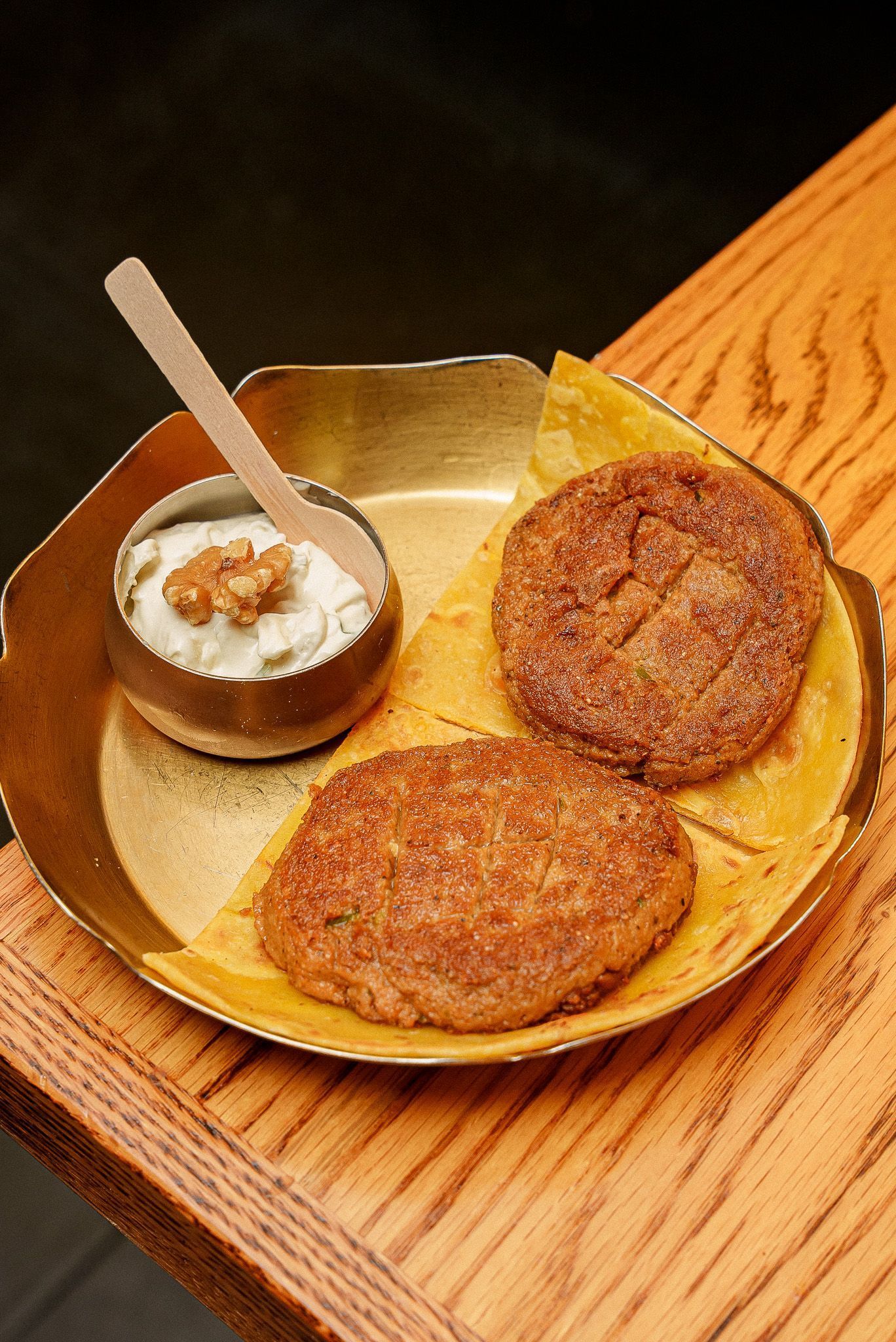 Traditional Indian dish served on a brass plate with curd and walnuts, showcasing Indian cuisine at Jazba.